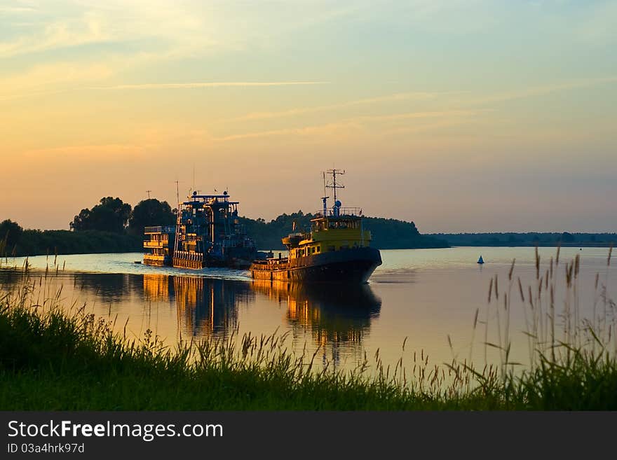 Steamers and barges glide across the water at sunset. Steamers and barges glide across the water at sunset