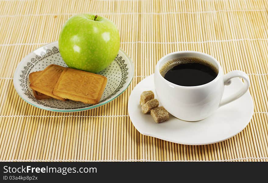 Cup of coffee, apple and biscuits on a plate stand on a napkin reed. Cup of coffee, apple and biscuits on a plate stand on a napkin reed