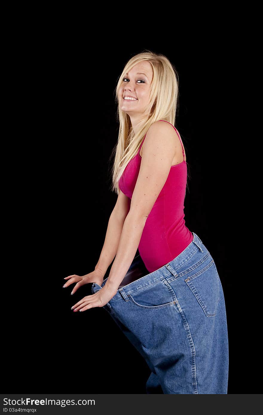 A woman with big pants is holding them out showing how much weight she has lost. A woman with big pants is holding them out showing how much weight she has lost.