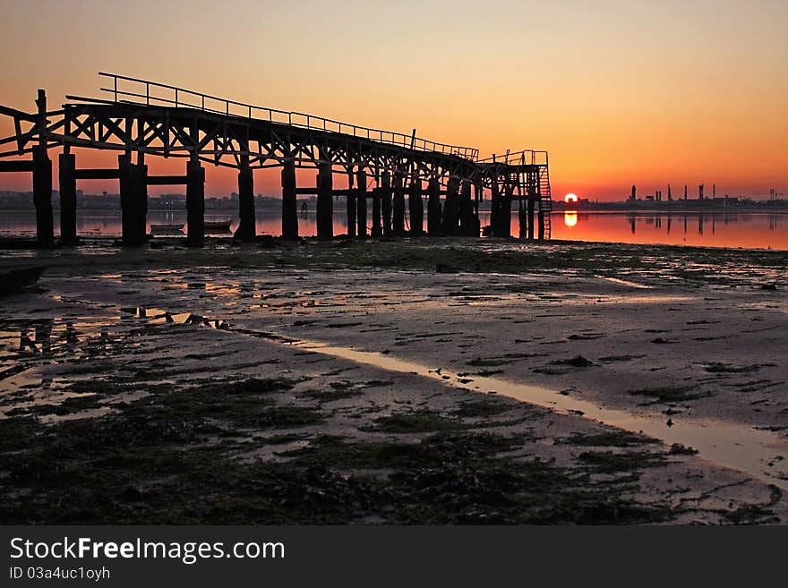 Low tide in the river, with motifs related to fishing activities, at the sunset