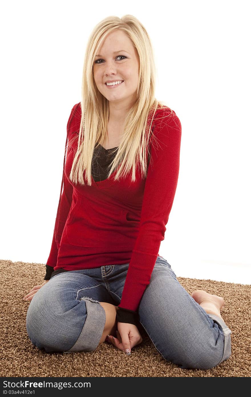 A woman in a red shirt is sitting on the floor with a smile. A woman in a red shirt is sitting on the floor with a smile.