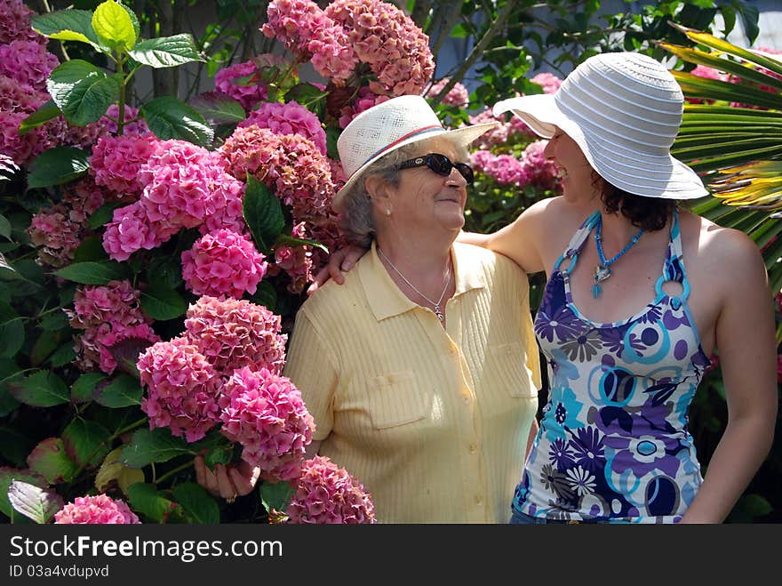 Old senior woman with her granddaughter smiling in garden. Old senior woman with her granddaughter smiling in garden.