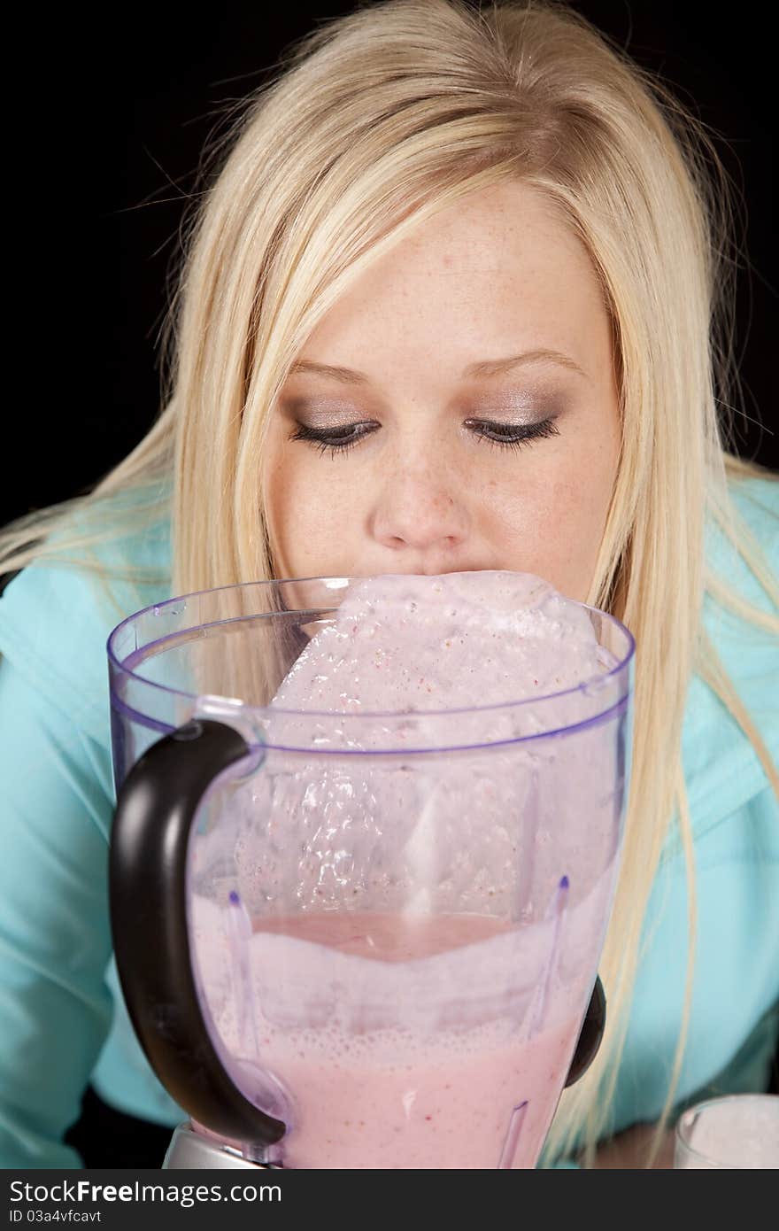 A woman is behind the blender looking into it. A woman is behind the blender looking into it.