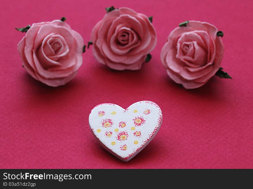 Patterned wooden heart and three pink roses. Patterned wooden heart and three pink roses