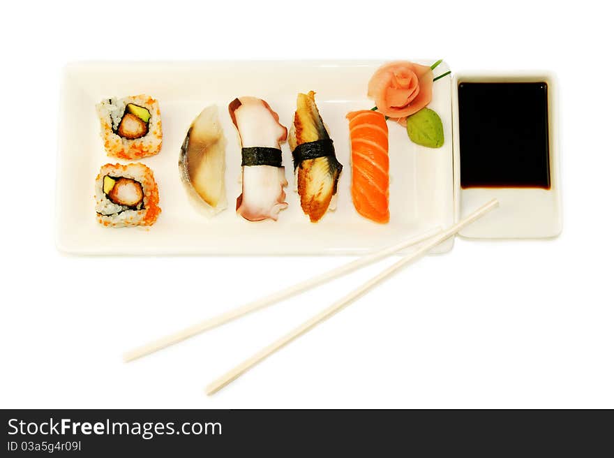 Variety of different types of sushi on the white plate over white background. Variety of different types of sushi on the white plate over white background