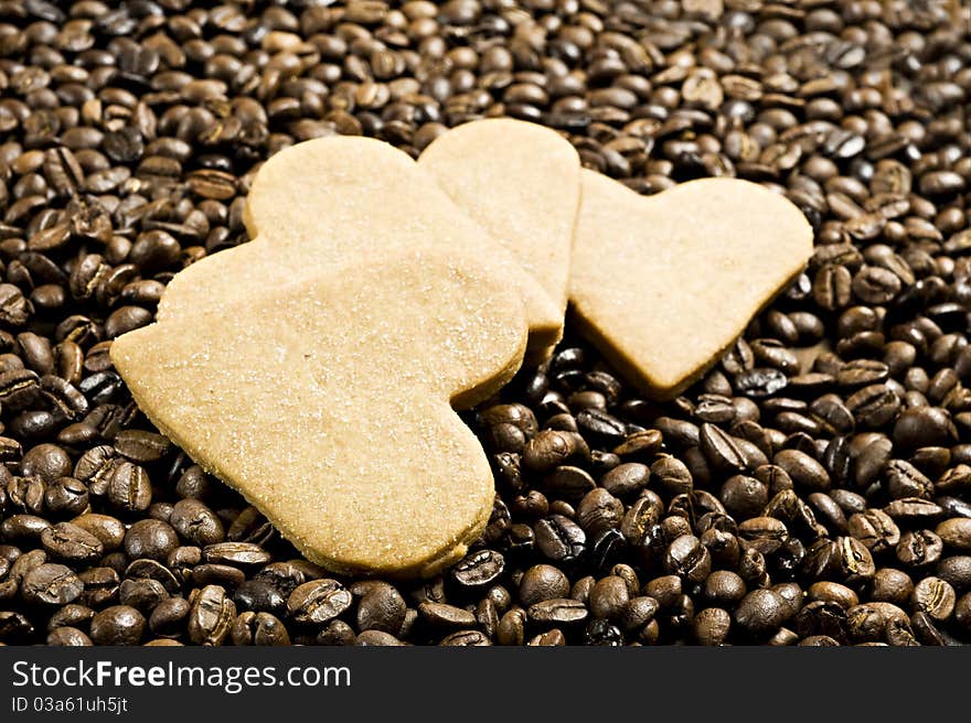 Close up background of a sugar coated heart shaped cookies in coffee beans very shallow depth of field and intentional low light. Close up background of a sugar coated heart shaped cookies in coffee beans very shallow depth of field and intentional low light