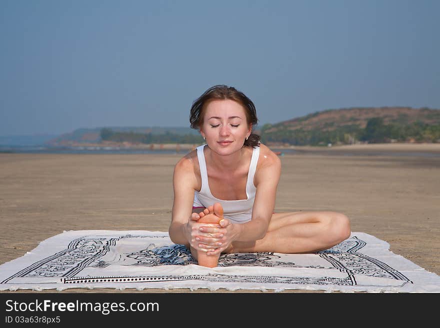 Young woman doing yoga on the beach