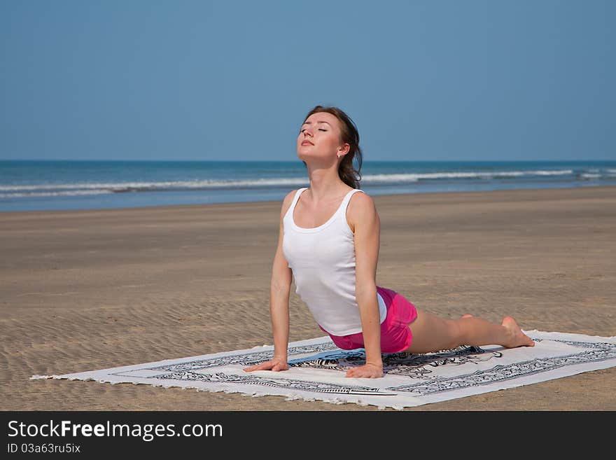 Young woman doing yoga on the beach