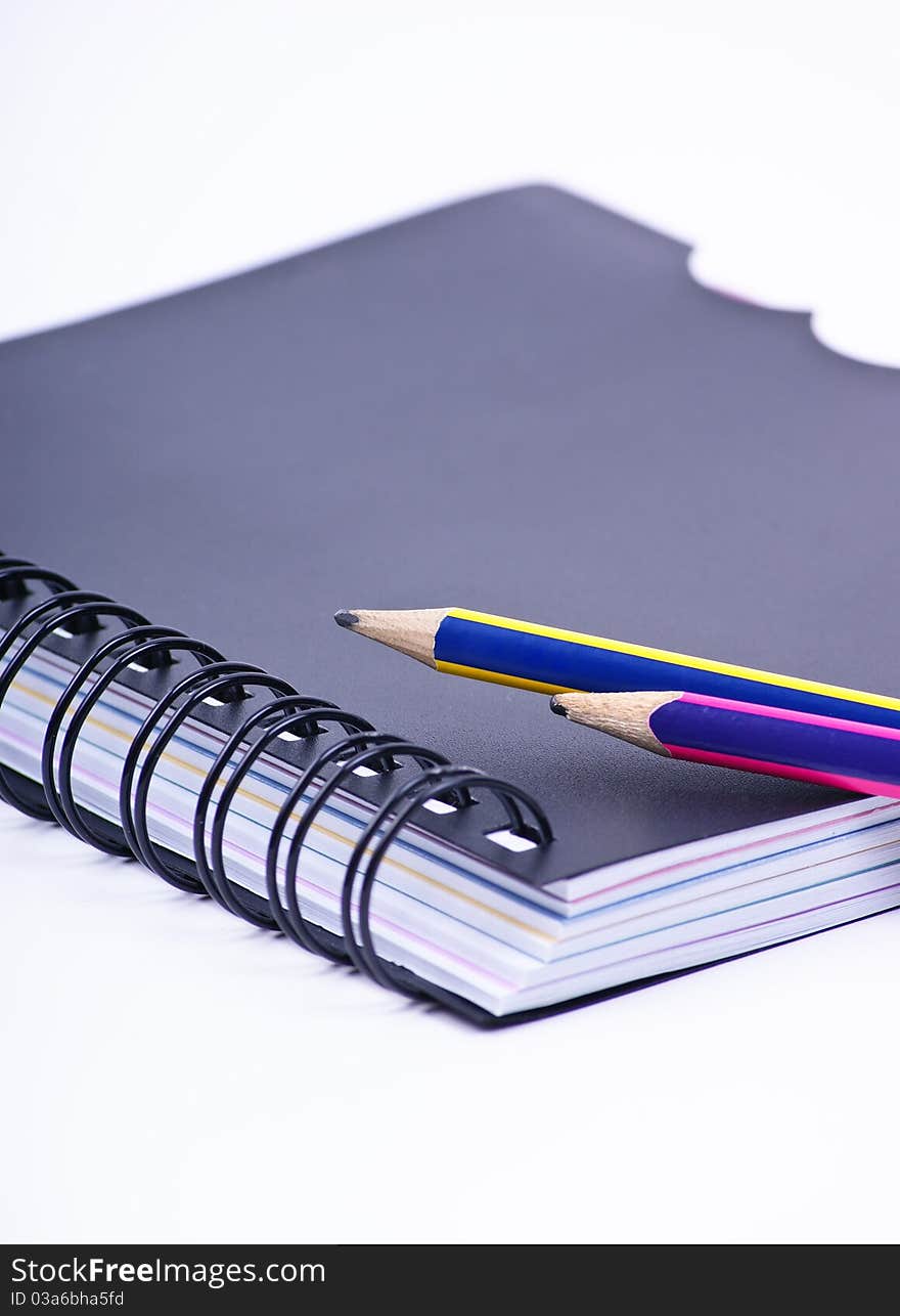 Notebook with a colored pencils on white background. Notebook with a colored pencils on white background