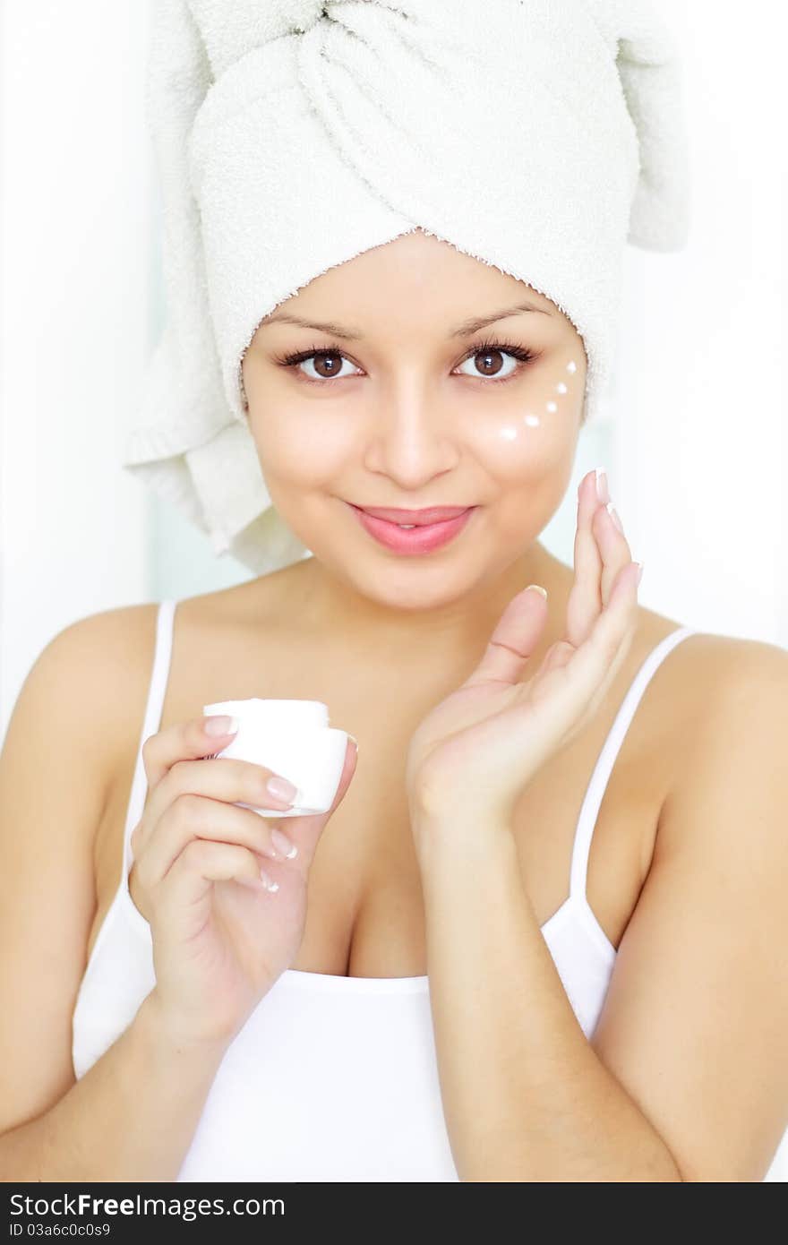 Girl applying cosmetic cream on skin on a light background in room. Girl applying cosmetic cream on skin on a light background in room