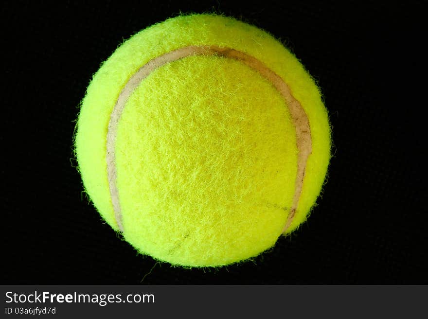 Green tennis ball on black background