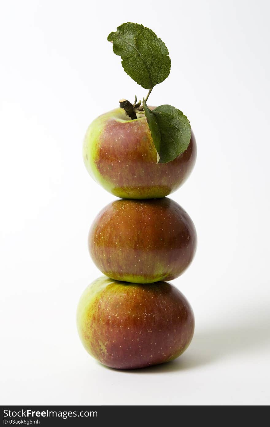 Three apples on white background with green leaf