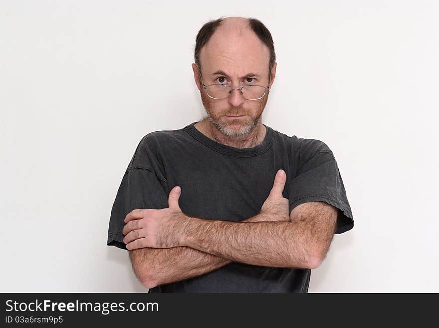 Unshaved disheveled man in spectacles frowning sullenly towards the camera. Unshaved disheveled man in spectacles frowning sullenly towards the camera