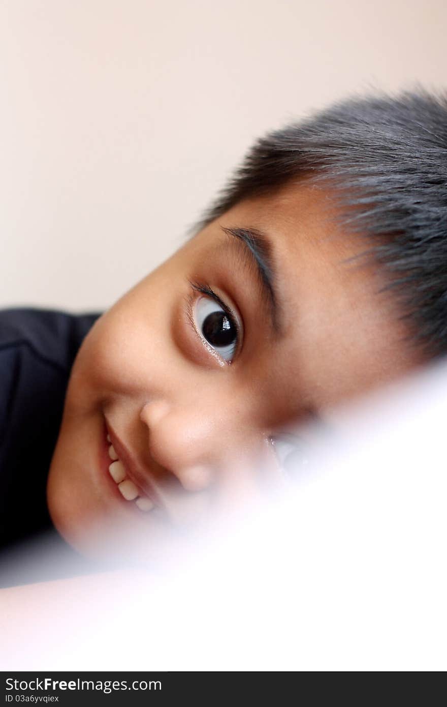 A boy glancing through a pillow with a big smile. A boy glancing through a pillow with a big smile