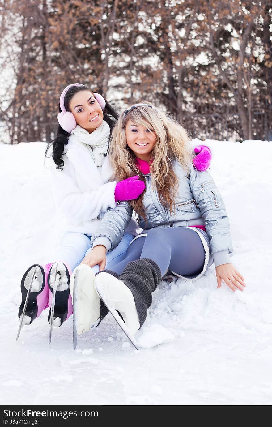 Two beautiful girls ice skating outdoor on a warm winter day (focus on the blond girl)