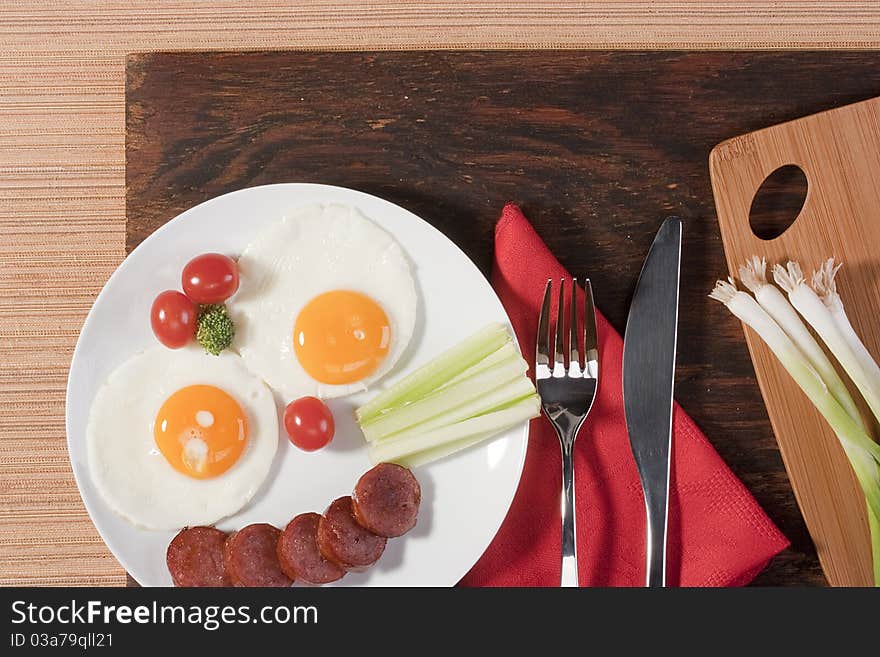 Fried eggs with fried sausage and vegetables.