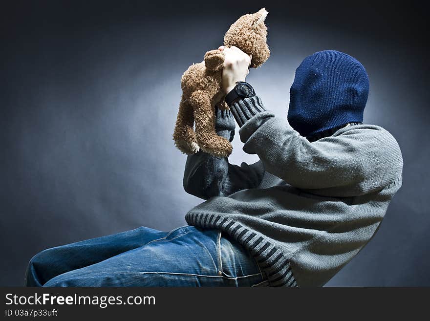 A hidden man sitting with his childhood teddy bear