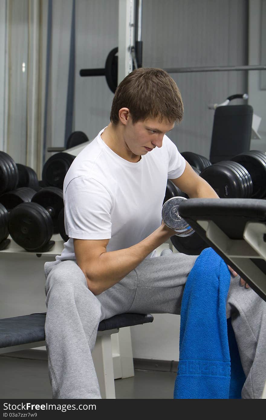 Young man exercising with dumbbell in fitness club. Young man exercising with dumbbell in fitness club