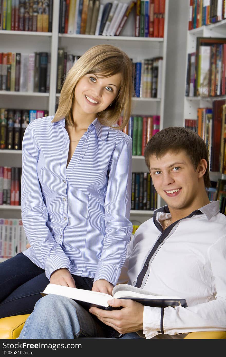 Young couple sitting in armchair with book