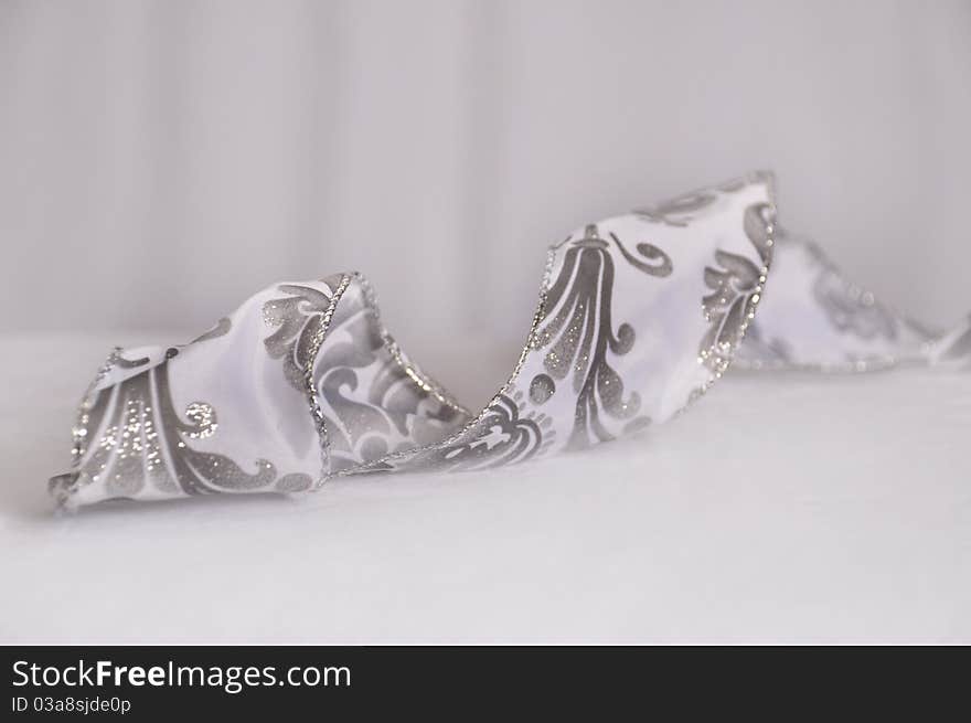 Silver twisted seasonal holiday ribbon on white background. Silver twisted seasonal holiday ribbon on white background