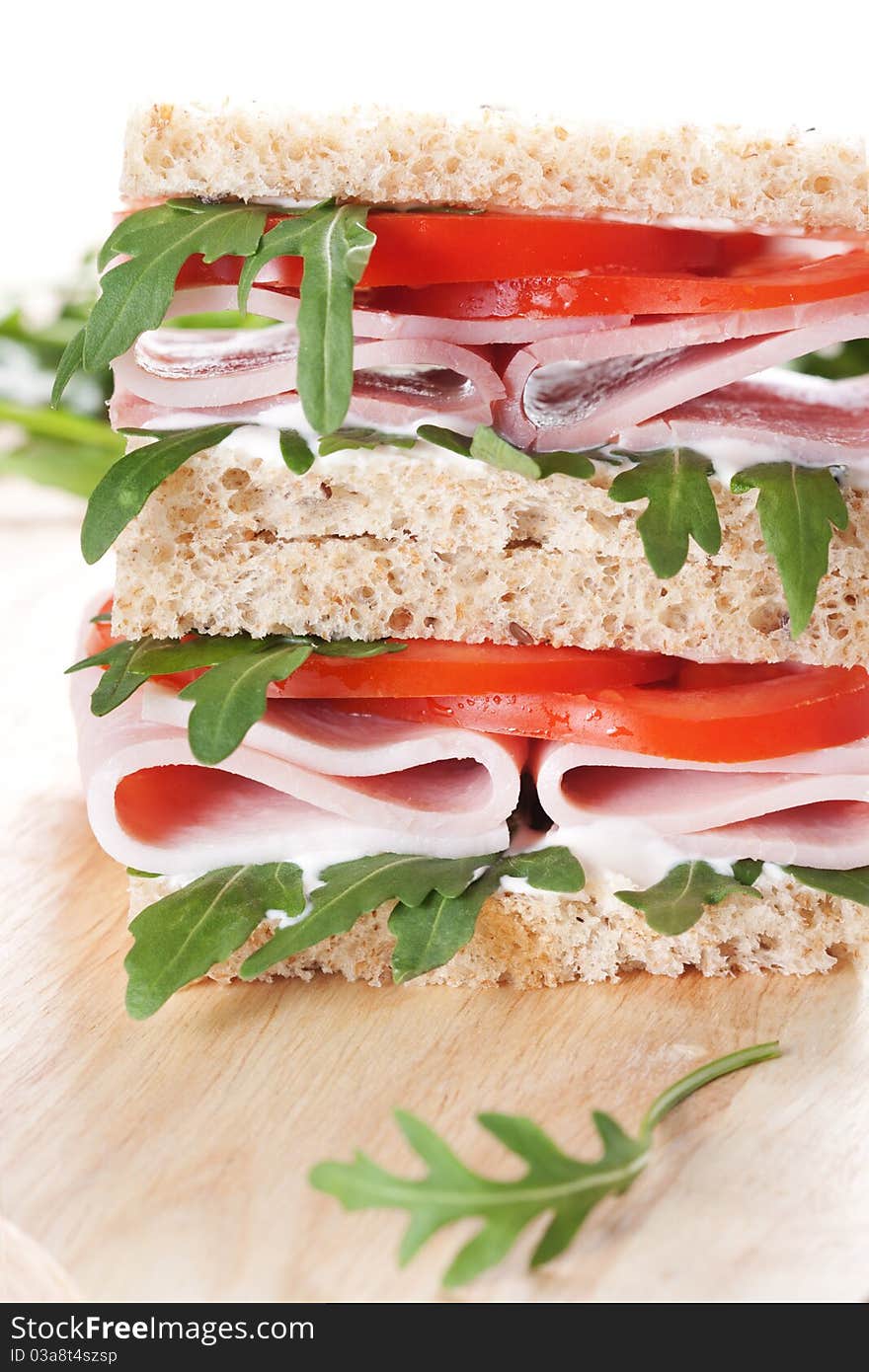 Sandwich with ham,tomato, and rucola salad on white