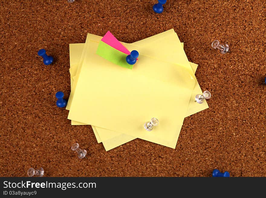 A group of messy post it notes on a cork board. A group of messy post it notes on a cork board.