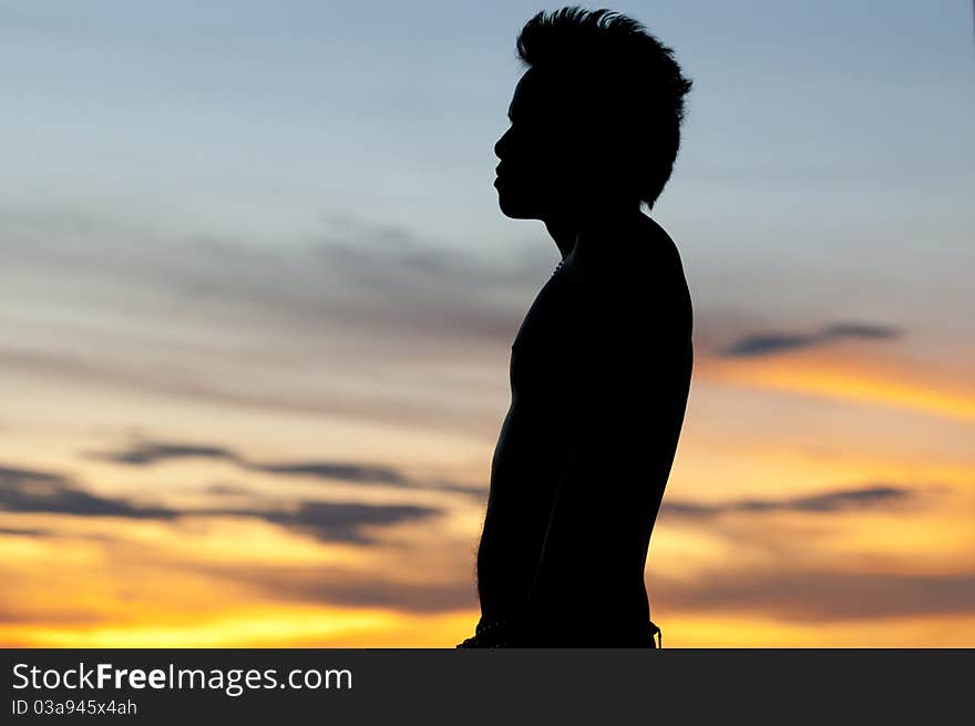 Asian male silouetted against sunset. Asian male silouetted against sunset