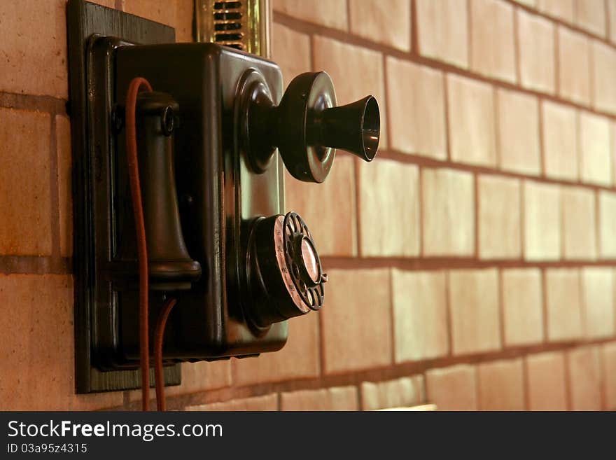 Old telephone mounted on a tiled wall in sepia. Old telephone mounted on a tiled wall in sepia