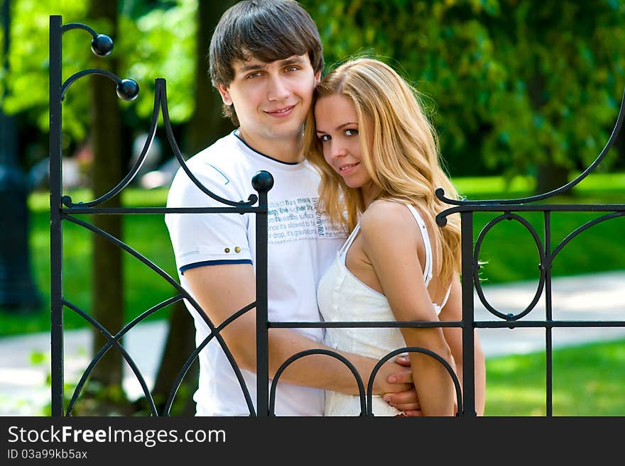 The young lovers are embracing a beautiful wall of an antique palace in the park. The young lovers are embracing a beautiful wall of an antique palace in the park