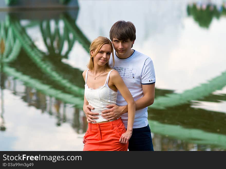 Behind the backs of young couples visible reflection in the water tracery bridge. Behind the backs of young couples visible reflection in the water tracery bridge