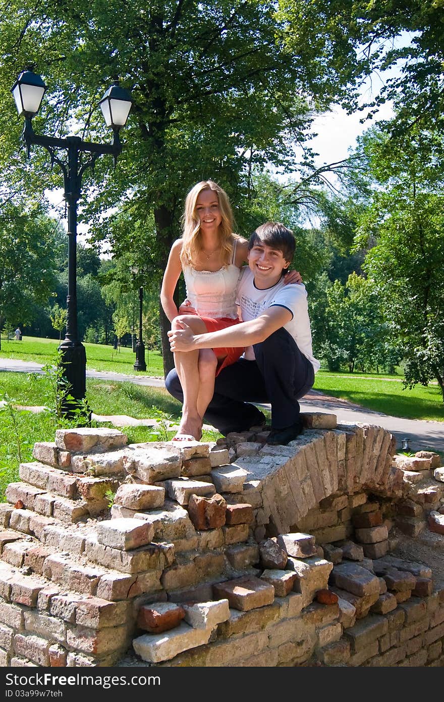 Sitting in the ruins of ancient brick walls of a young couple happily laughing. Sitting in the ruins of ancient brick walls of a young couple happily laughing