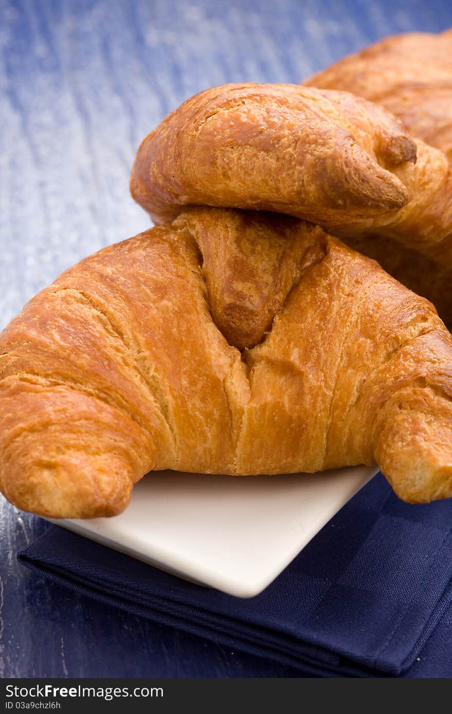 Photo of delicious fresh croissants for breakfast on a soft blue background. Photo of delicious fresh croissants for breakfast on a soft blue background