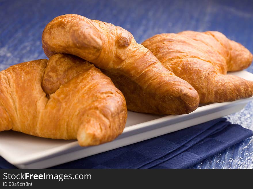 Photo of delicious fresh croissants for breakfast on a soft blue background. Photo of delicious fresh croissants for breakfast on a soft blue background