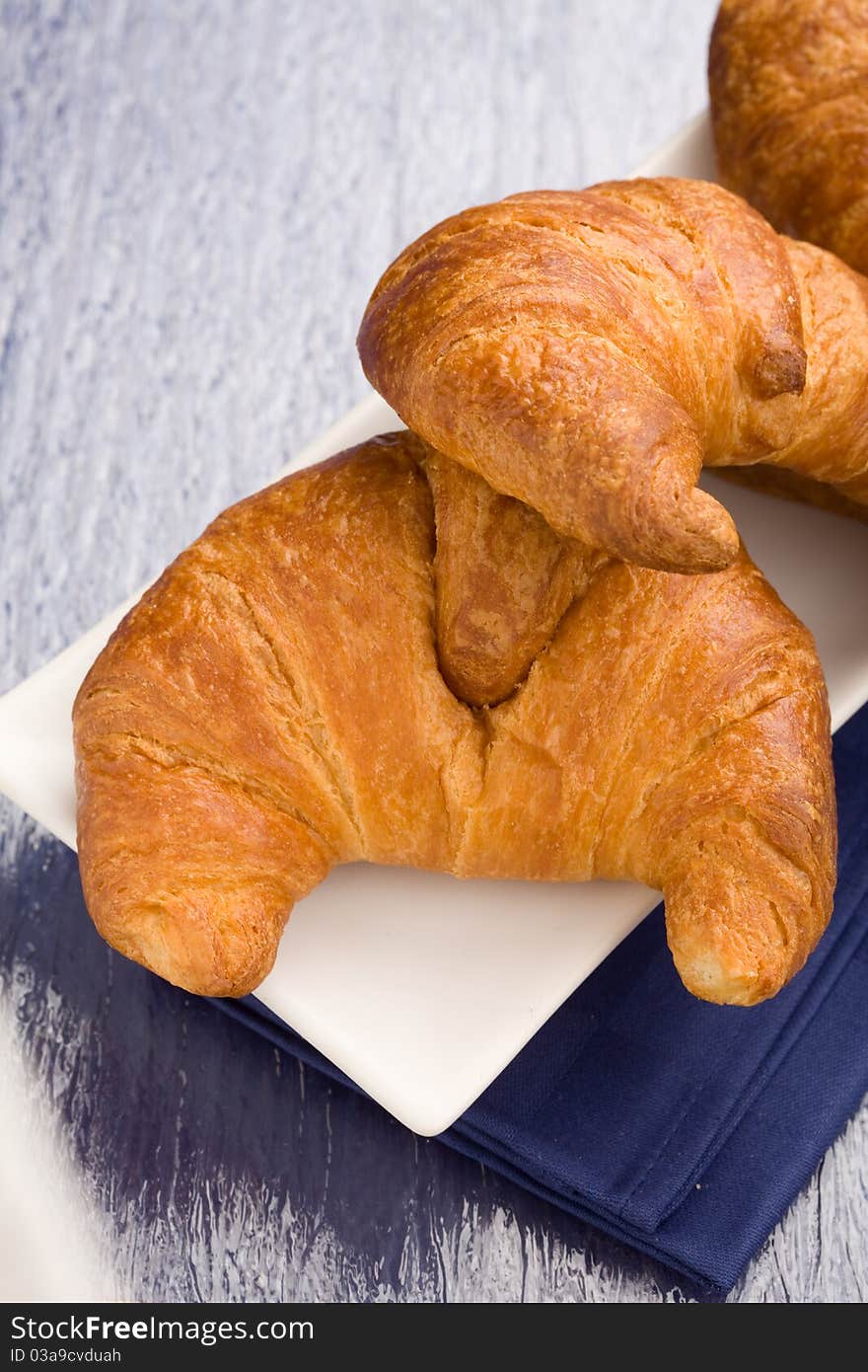 Photo of delicious fresh croissants for breakfast on a soft blue background. Photo of delicious fresh croissants for breakfast on a soft blue background