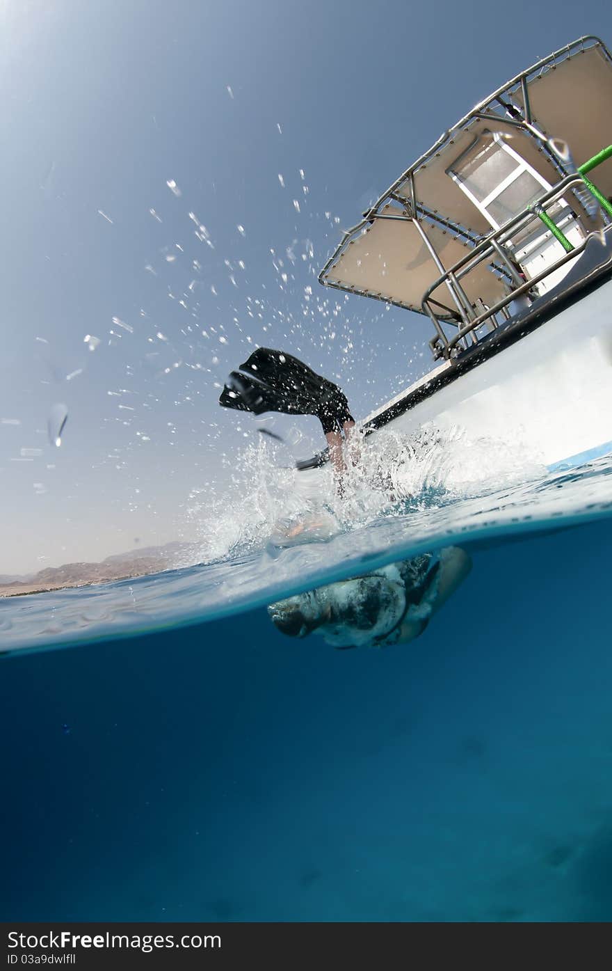 Scuba diver enters the water from a boat, Over under shot. Scuba diver enters the water from a boat, Over under shot.