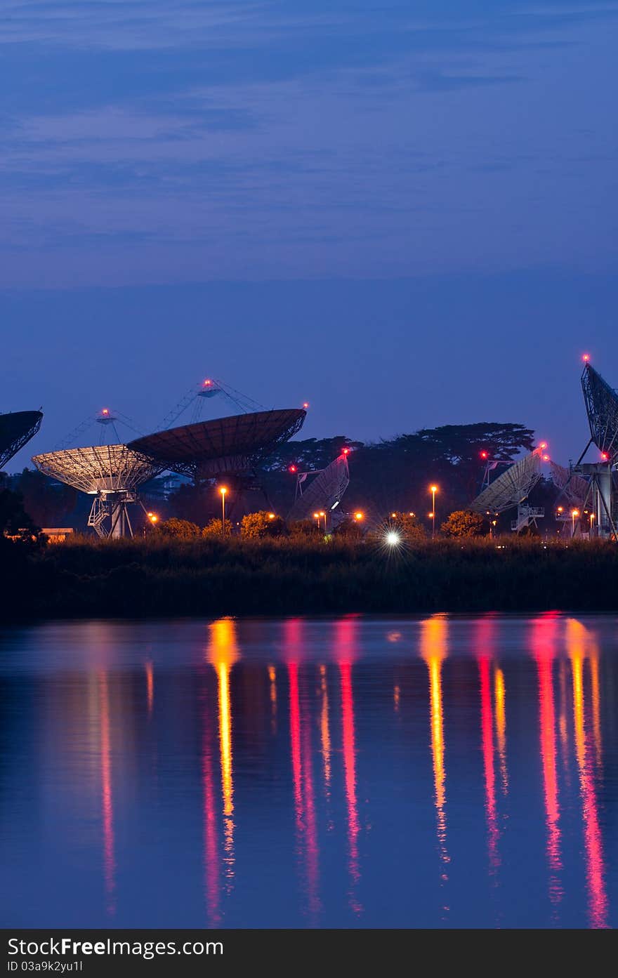 Colourful lights from various satellite dishes reflecting off a calm water catchment area. Colourful lights from various satellite dishes reflecting off a calm water catchment area