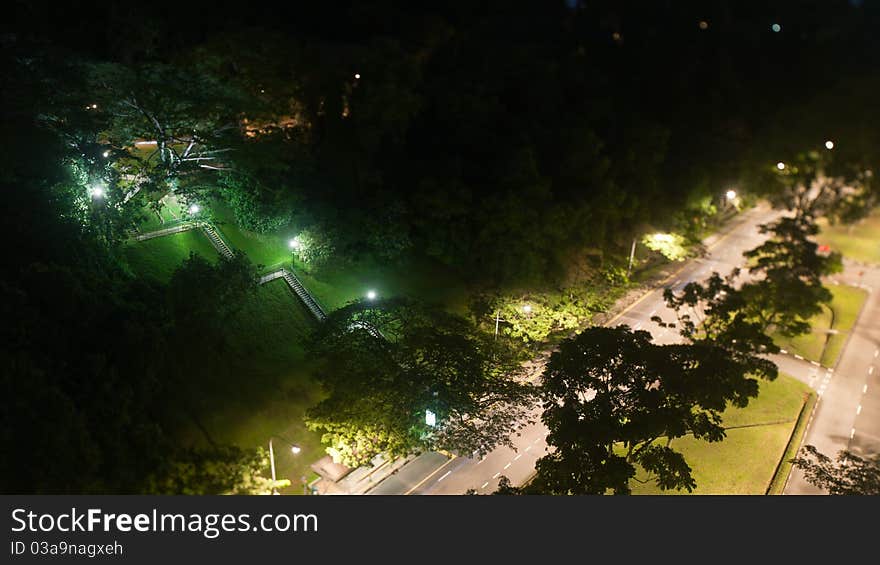 A staggered formation stairs leading perpendicularly to a straight road, void of human element in the lonely night. A staggered formation stairs leading perpendicularly to a straight road, void of human element in the lonely night