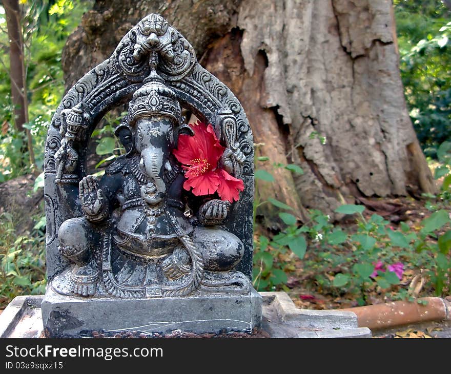 A stone ganesh deity out in the forest.