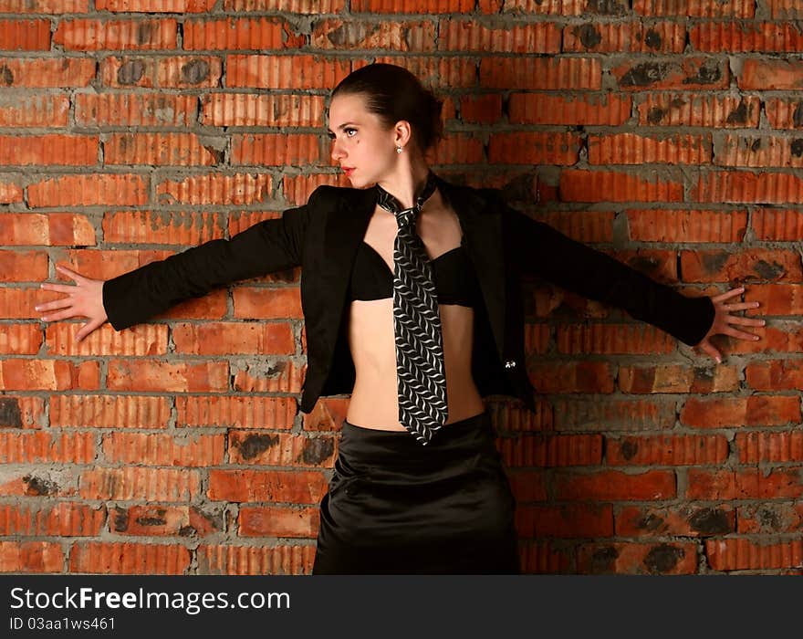 Girl in black suit stands back to brickwall. Girl in black suit stands back to brickwall.