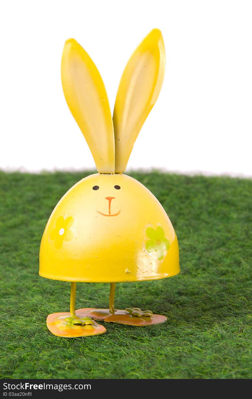 Yellow egg-shaped rabbit staying on green grass. Yellow egg-shaped rabbit staying on green grass