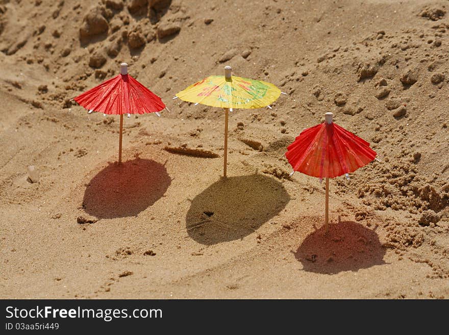 Three toy umbrella on sand. close-up. Three toy umbrella on sand. close-up.