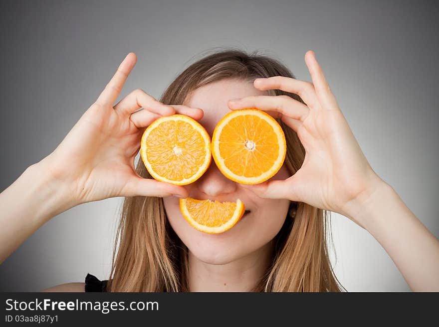 Beautiful blond girl using orange as eyes. Beautiful blond girl using orange as eyes