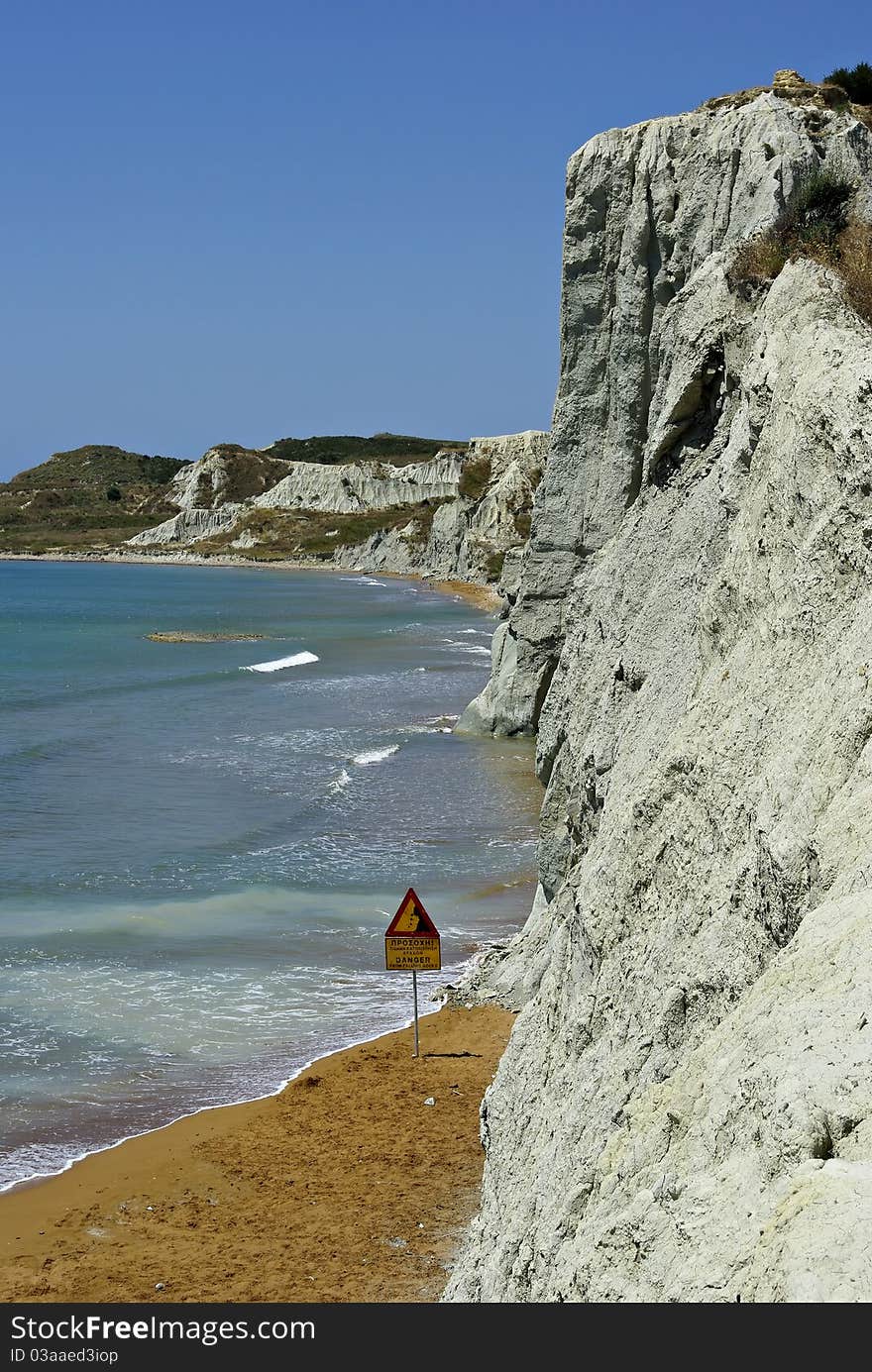 Sandy beach and dangerous cliffs at sunny summer day.