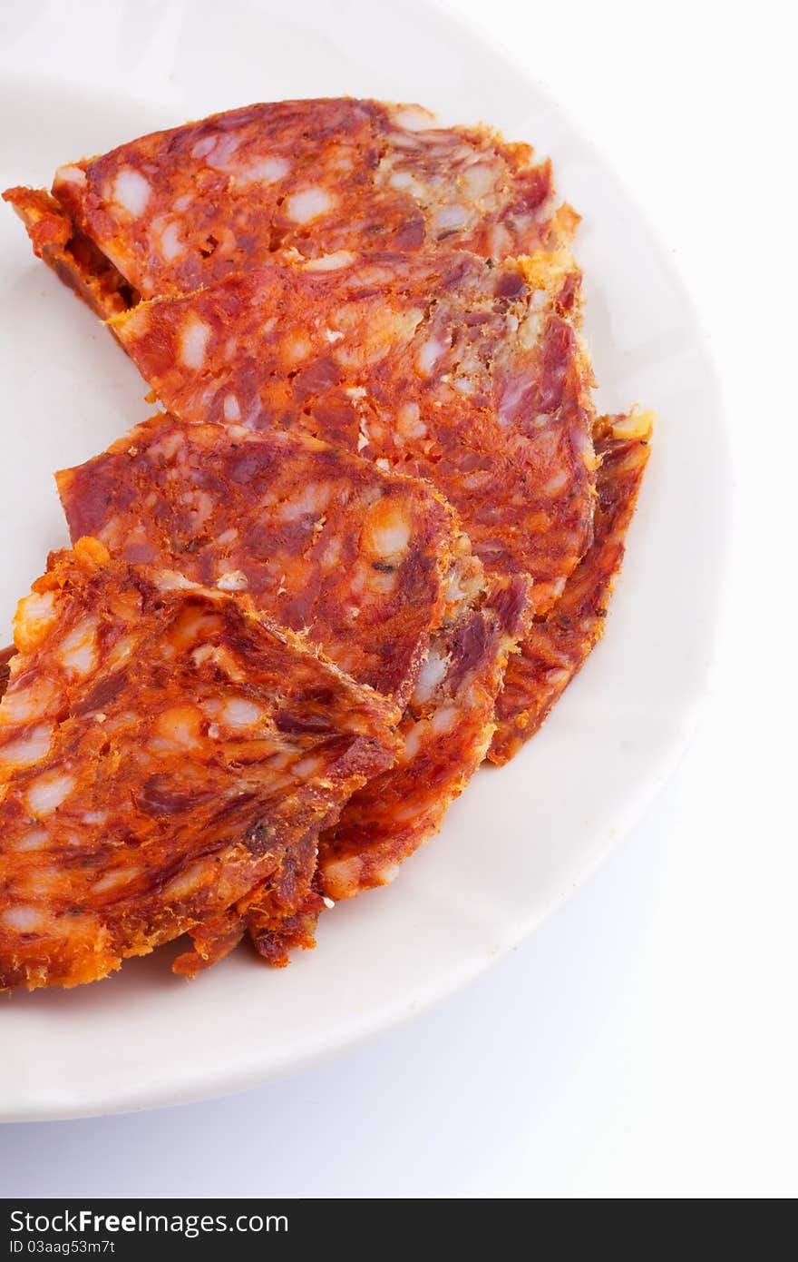 Raw thinly sliced sausage in a white bowl on a white background. Raw thinly sliced sausage in a white bowl on a white background