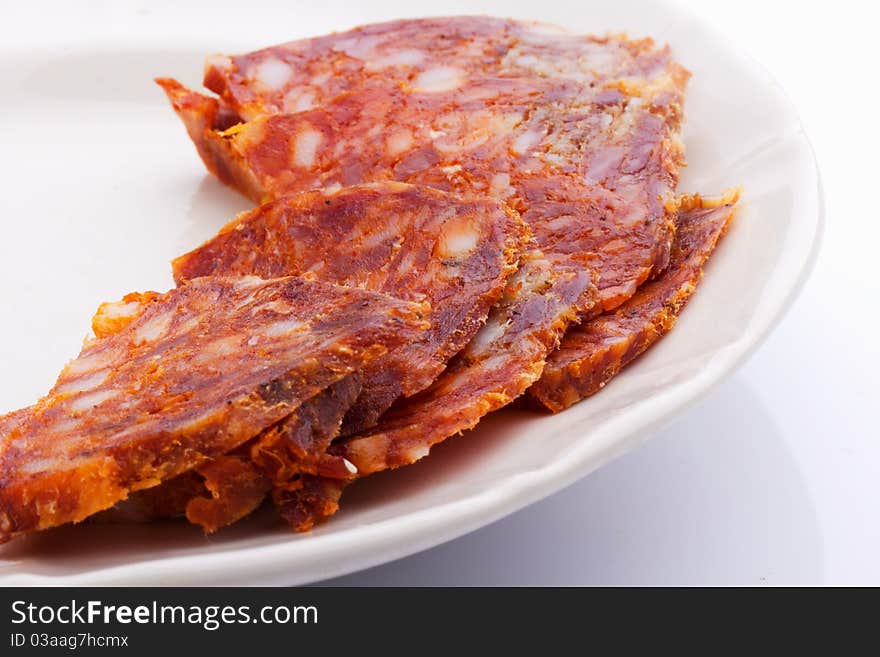 Raw thinly sliced sausage in a white bowl on a white background. Raw thinly sliced sausage in a white bowl on a white background