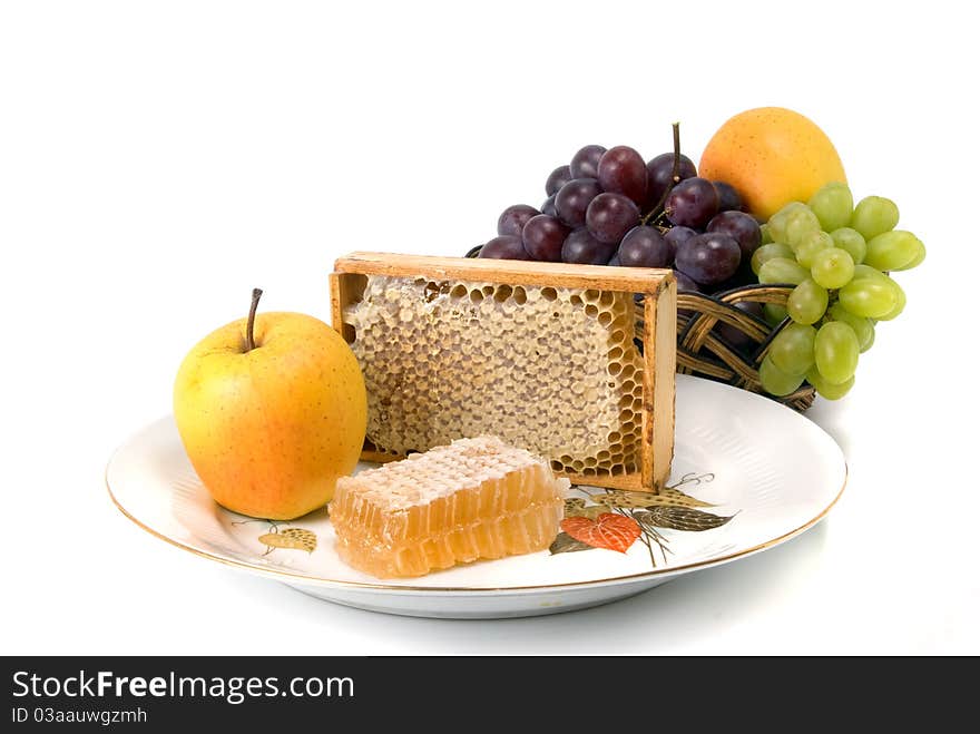 Honeycomb in border with fruits on dish