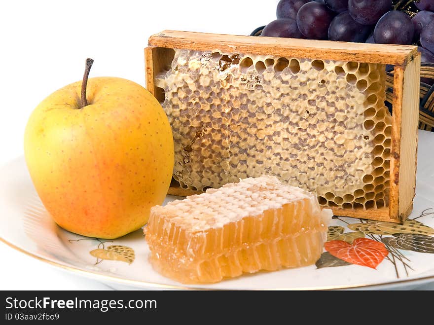 Honeycomb in border with fruits on dish