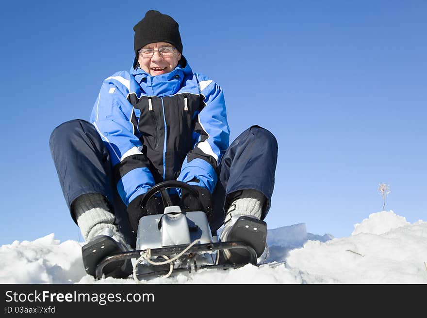 Middle-aged man sledding. Sky on background.