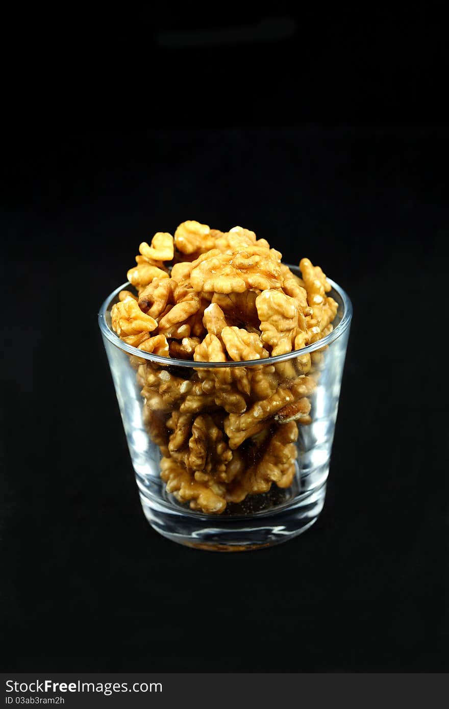 Walnut kernels in a cup on black background