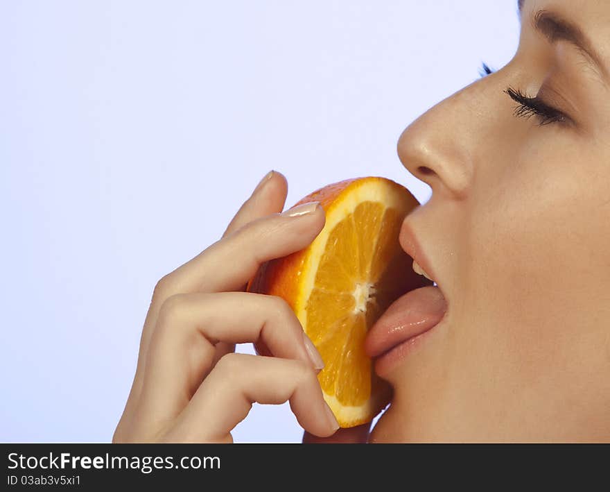 Young woman enjoying a slice of orange